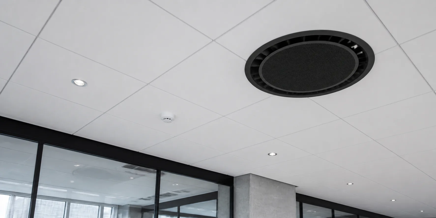 Black round ceiling cassette integrated into the ceiling of a modern commercial space